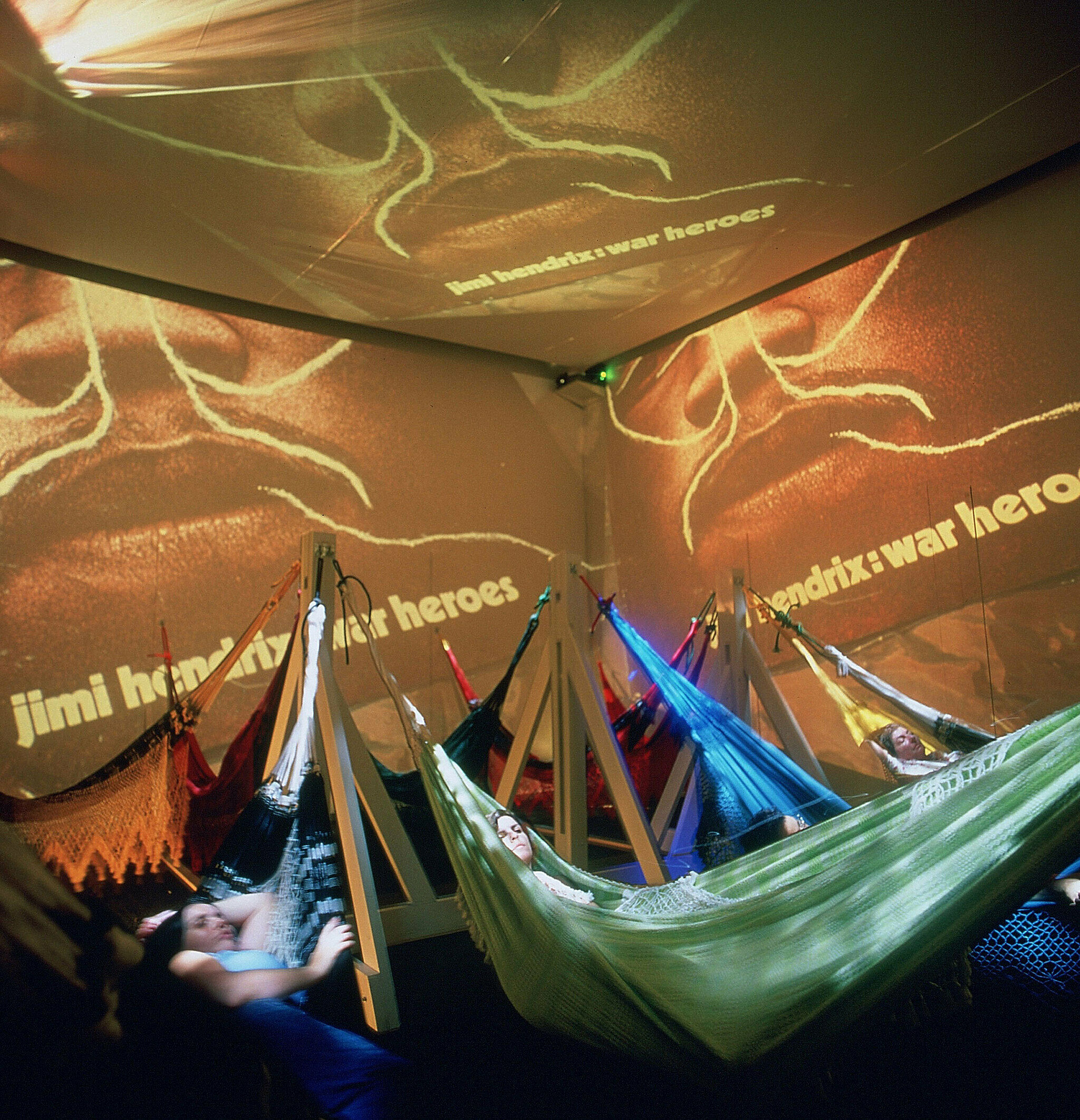 projected images on walls surrounding people in hammocks