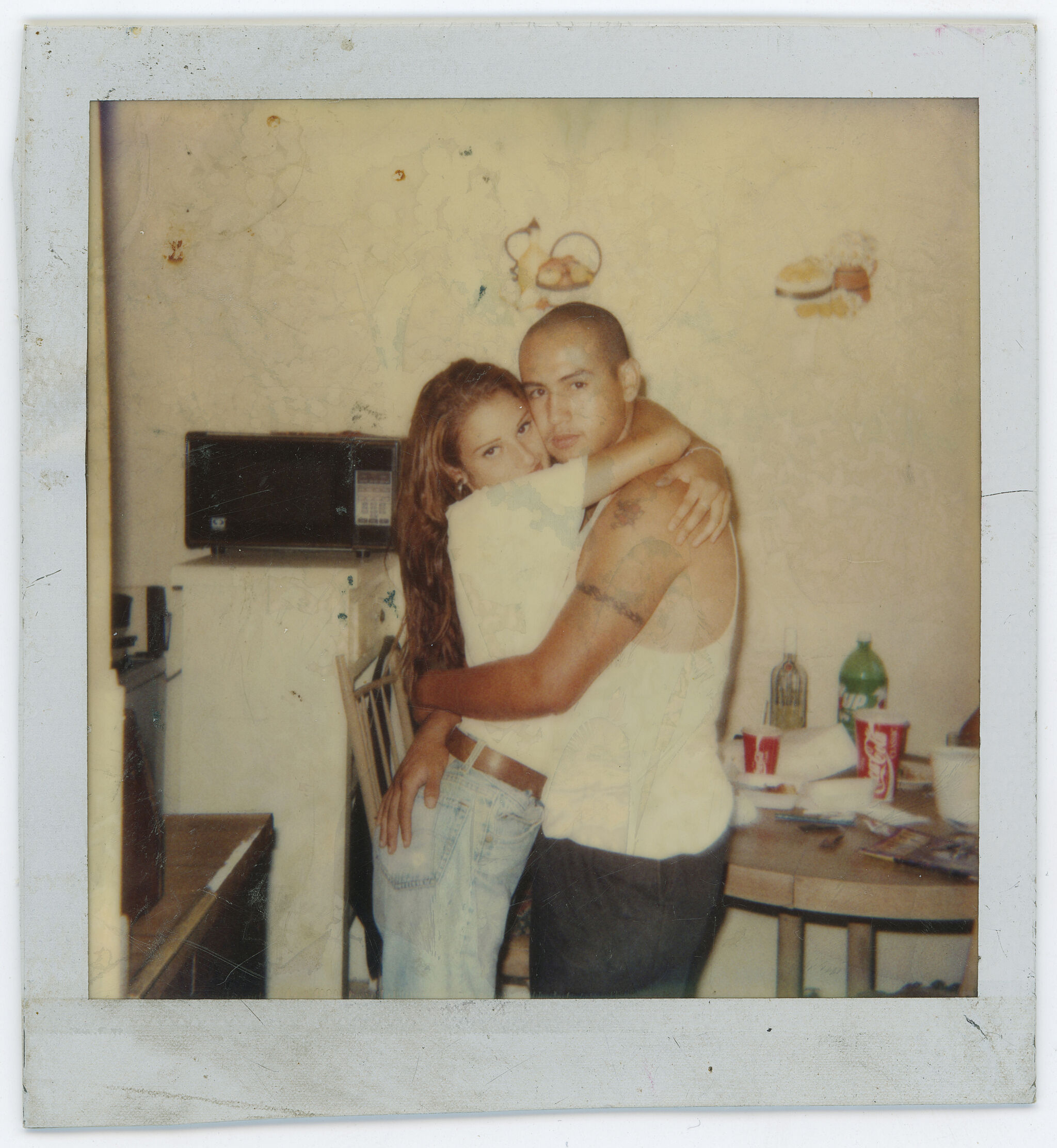 A photograph of two people hugging each other and looking at the camera.