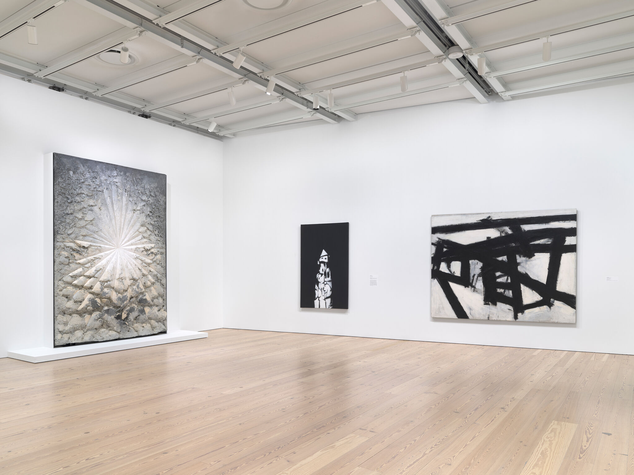 A gallery with white walls and three large artworks.