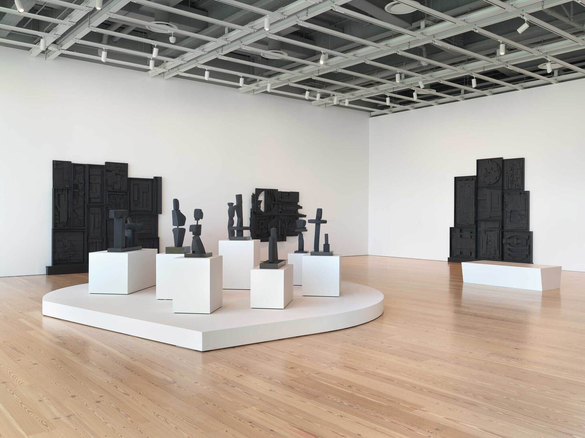 Black sculptures made of found objects in a modern art gallery.